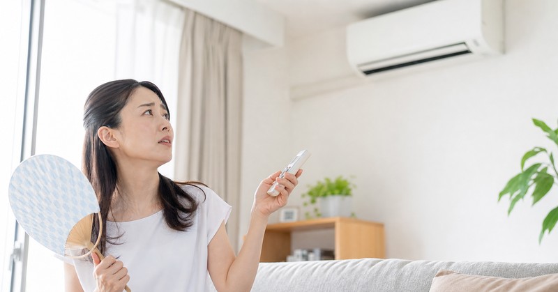 冷えないエアコンを見上げて困る女性